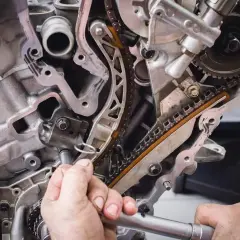 Mechanik naprawia rozrząd silnika. Zepsuta poduszka silnika objawy mogą być różne, np. wibracje.