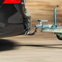 Czarne auto z hakiem holowniczym ciągnie przyczepę.