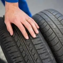 Dłoń mechanika dotyka bieżnika opony Hankook, sugerując pozytywne opony Hankook opinie.