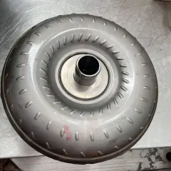 Metalowy konwerter momentu obrotowego, jeden z rodzajów sprzęgieł, leży na metalowej powierzchni.