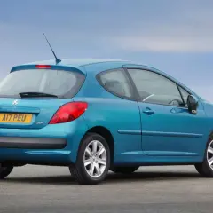 Niebieski Peugeot 207 1.4 HDI z tablicą rejestracyjną AI7 PEU stoi na tle błękitnego nieba.