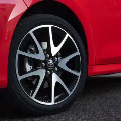 Czerwona kropka na oponie nowego, czerwonego samochodu. Felga z logo Toyoty.