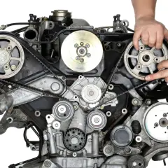 Mechanik wykonuje wymianę paska rozrządu w silniku samochodowym, precyzyjnie manipulując elementami układu.