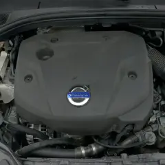Silnik Volvo D4 pod czarną osłoną z niebieskim logo. Widoczne przewody i elementy układu chłodzenia.