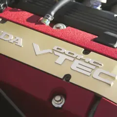 Złota pokrywa zaworów z napisem HONDA VTEC w czerwonej obudowie silnika.