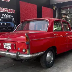 Czerwony Peugeot 404 z tablicą rejestracyjną z Peru, zaparkowany przed sklepem z częściami samochodowymi.