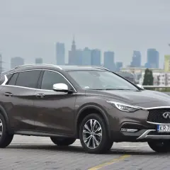Brązowy Infiniti QX30 na tle miejskiej panoramy. Elegancki crossover gotowy na miejskie wyzwania.