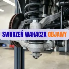 Widok z bliska na element zawieszenia samochodu, gdzie widać sworzeń wahacza. Objawy jego zużycia mogą prowadzić do problemów z prowadzeniem pojazdu.