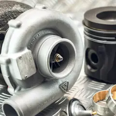 Turbosprężarka i tłok Kolbenschmidt na metalowej powierzchni.