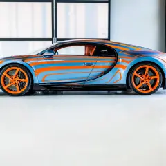 Niebiesko-pomarańczowy Bugatti Chiron Super Sport z dynamicznym wzorem falistych linii i pomarańczowymi felgami.