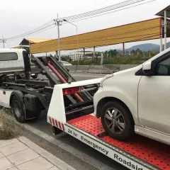 Pomoc drogowa w akcji: białe auto jest ładowane na lawetę. Widać, jak holować auto, gdy jest potrzebna pomoc.