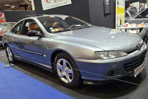 Elegancki, srebrny Peugeot 406 coupe z brązową tapicerką, prezentowany na wystawie.
