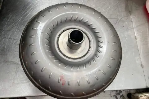 Metalowy konwerter momentu obrotowego, jeden z rodzajów sprzęgieł, leży na metalowej powierzchni.