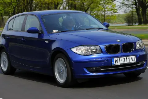 Niebieskie BMW Serii 1 w ruchu drogowym. Kierowca w niebieskiej koszulce. Wiele pozytywnych bmw seria 1 opinie potwierdza jego jakość.