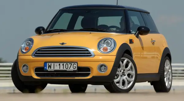 Żółty mini r50 z czarnym dachem i felgami stoi na zewnątrz.