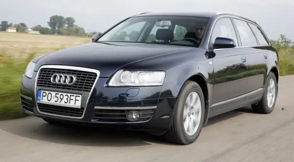 Ciemnogranatowe Audi A6 C6 2.7 TDI Avant w ruchu, z widocznym kierowcą i polskimi tablicami rejestracyjnymi.