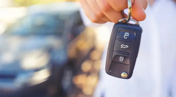 Dłoń trzyma kluczyk samochodowy. Czy to objawy uszkodzonego immobilizera? Auto nie odpala.