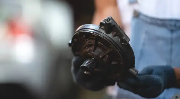 Mechanik w rękawiczkach trzyma element układu kierowniczego – serwo.