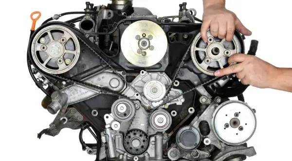Mechanik wykonuje wymianę paska rozrządu w silniku samochodowym, precyzyjnie manipulując elementami układu.