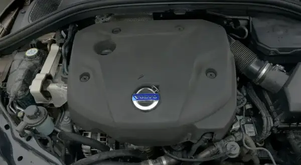 Silnik Volvo D4 pod czarną osłoną z niebieskim logo. Widoczne przewody i elementy układu chłodzenia.