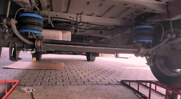 Podwozie pojazdu z zamontowanym zawieszeniem hydropneumatycznym. Dwa niebieskie miechy pneumatyczne są widoczne po obu stronach osi.