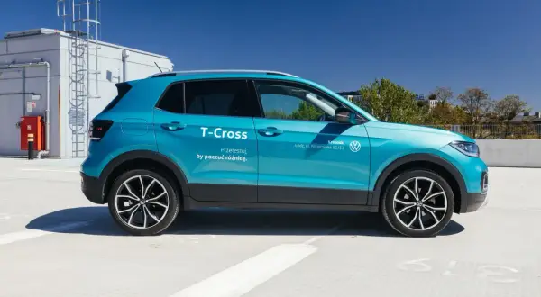 Błękitny Volkswagen T-Cross, idealny mały SUV dla żony, zaparkowany na dachu budynku.
