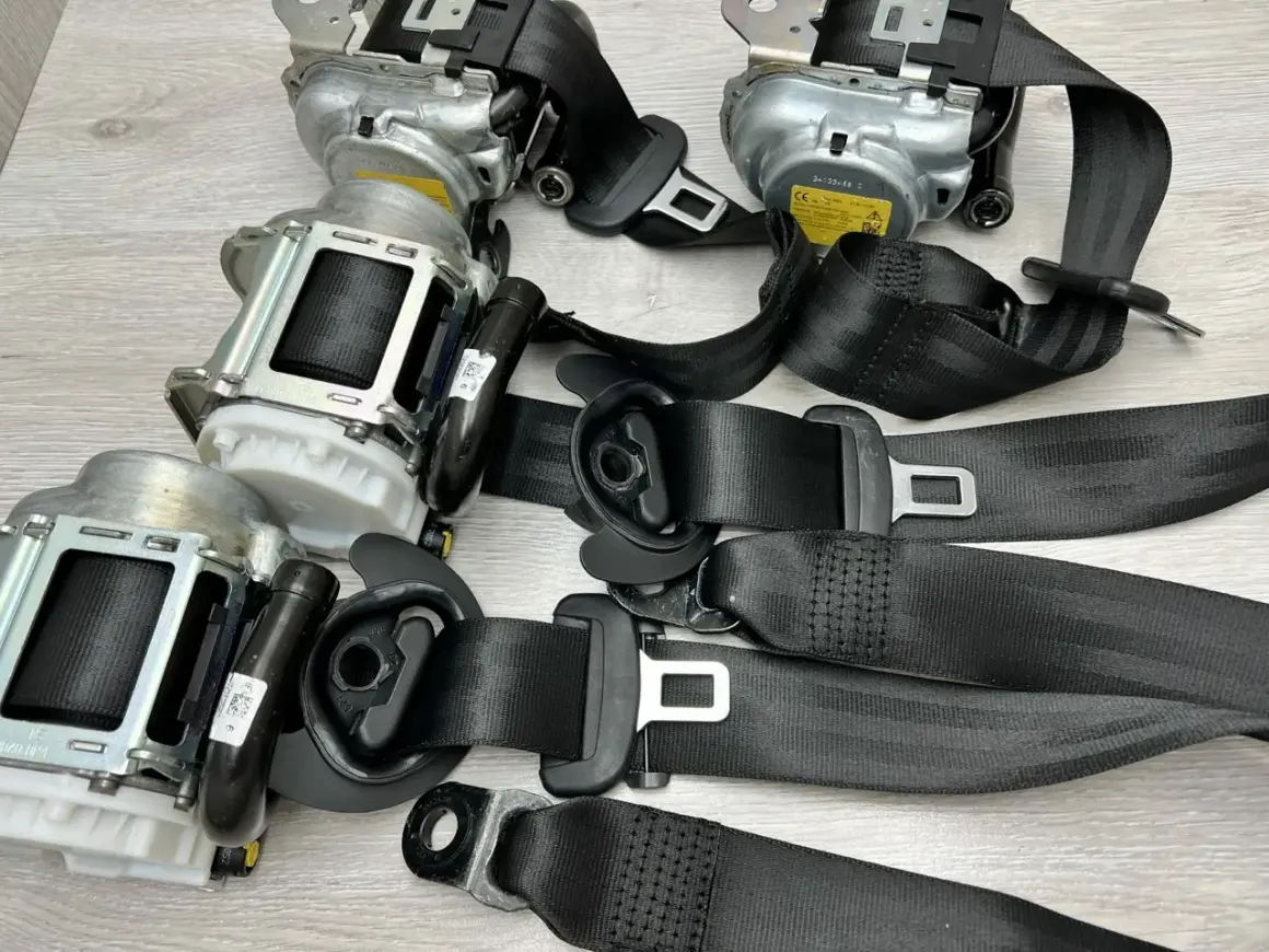 Zastanawiasz się, ile kosztuje wymiana pasów bezpieczeństwa? Na zdjęciu widać kilka kompletnych mechanizmów pasów z klamrami, gotowych do montażu.