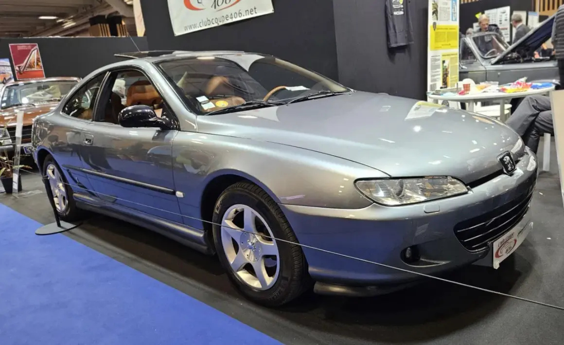 Elegancki, srebrny Peugeot 406 coupe z brązową tapicerką, prezentowany na wystawie.