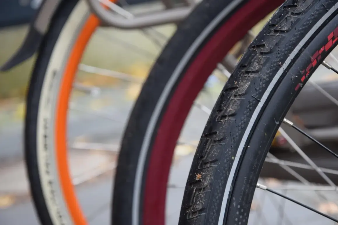 Zbliżenie na opony rowerowe 29 cali z widocznymi bieżnikami i obręczami w różnych kolorach.