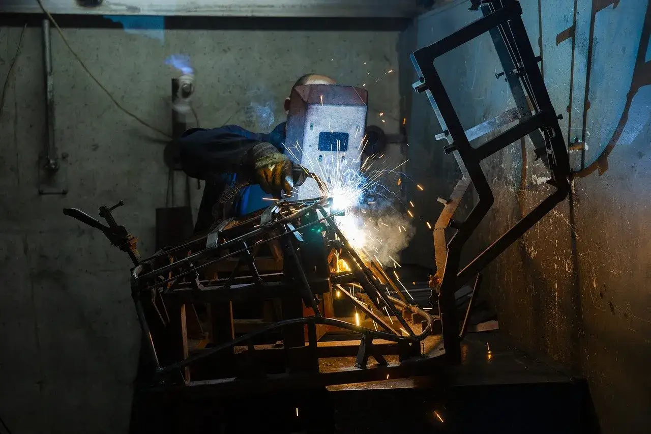 Spawanie aluminium migomatem. Iskry sypią się podczas precyzyjnego łączenia elementów metalowej konstrukcji.