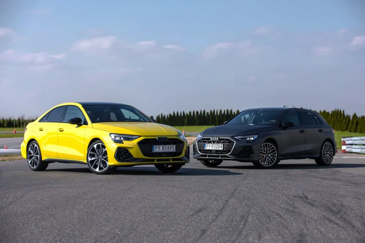 Dwa Audi A3: żółty sedan i ciemnoszary hatchback, prezentują swoje wymiary na torze.