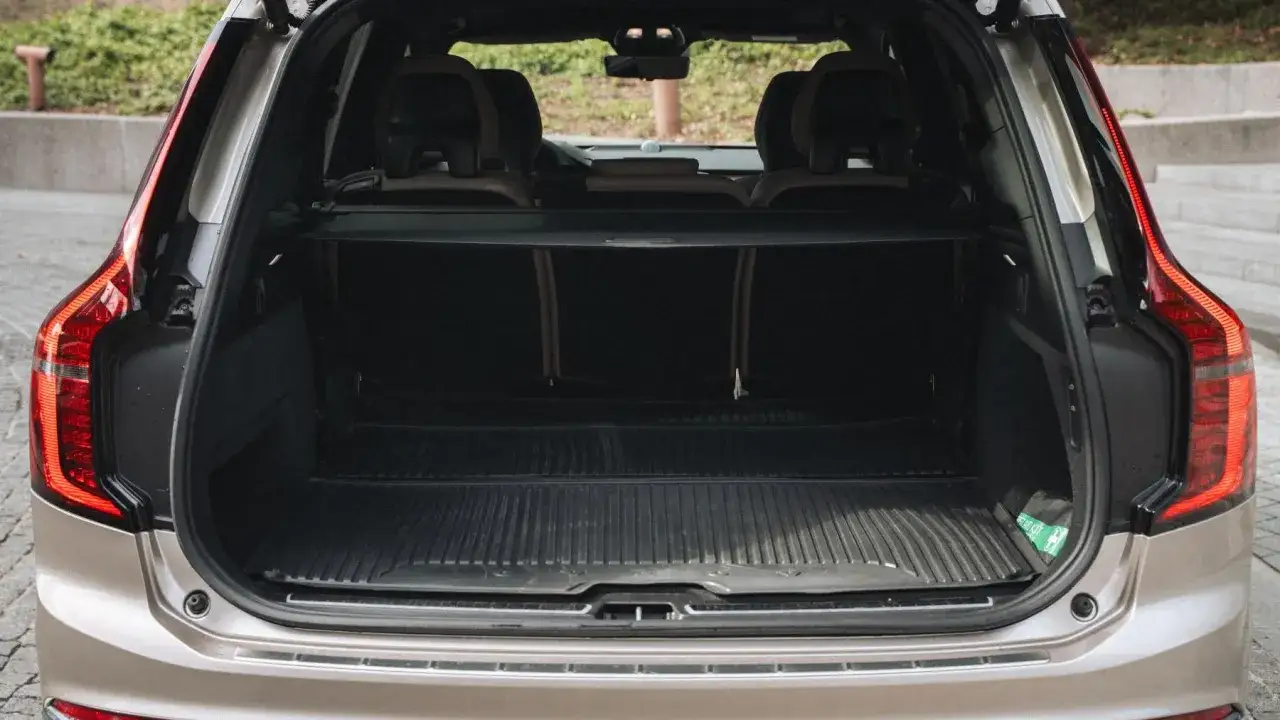 Pusta przestrzeń bagażowa Volvo XC90 V8, gotowa na rodzinne wakacje. W rogu widoczna apteczka.