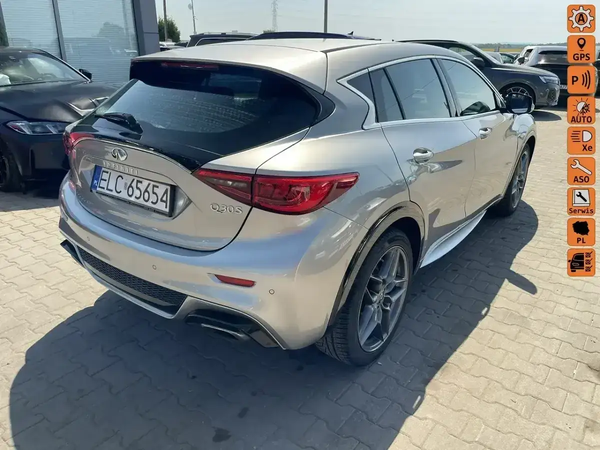 Srebrny Infiniti QX30 z czarnym spoilerem i przyciemnianymi szybami, zaparkowany na zewnątrz.