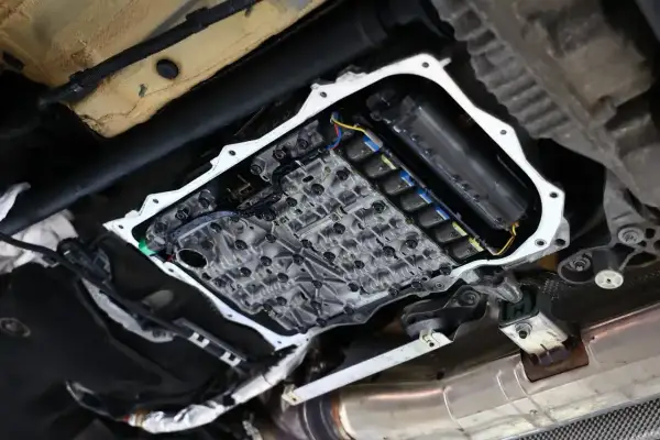 Widok od spodu na otwartą skrzynię biegów, gdzie widać skomplikowany mechanizm zaworów i cewek, kluczowy dla płynnego powershift.