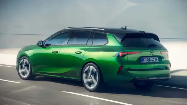 Zielony Opel Astra kombi, jeden z nowoczesnych opel modele, pędzi po drodze.