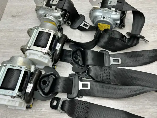 Zastanawiasz się, ile kosztuje wymiana pasów bezpieczeństwa? Na zdjęciu widać kilka kompletnych mechanizmów pasów z klamrami, gotowych do montażu.