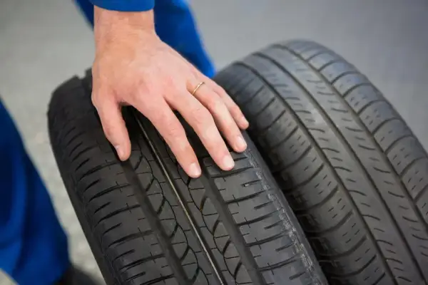 Dłoń mechanika dotyka bieżnika opony Hankook, sugerując pozytywne opony Hankook opinie.