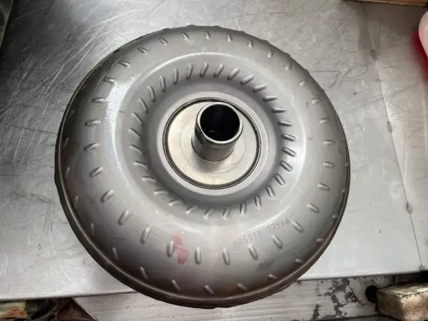 Metalowy konwerter momentu obrotowego, jeden z rodzajów sprzęgieł, leży na metalowej powierzchni.