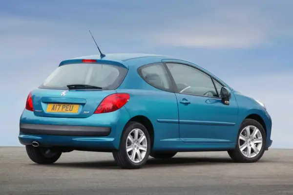 Niebieski Peugeot 207 1.4 HDI z tablicą rejestracyjną AI7 PEU stoi na tle błękitnego nieba.
