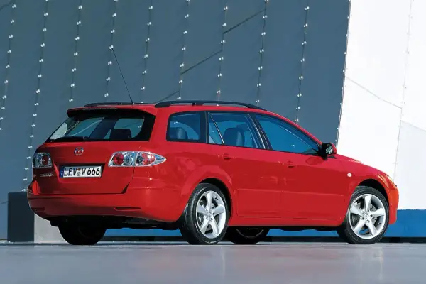 Czerwona Mazda 6 GG kombi stoi na tle nowoczesnego budynku.
