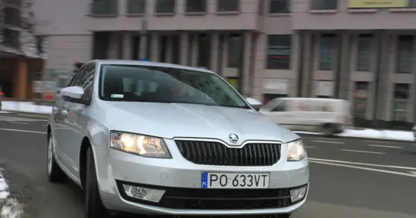 Srebrna Skoda Octavia 1.6 TDI jedzie ulicą miasta.