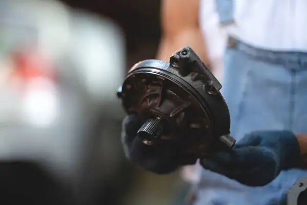 Mechanik w rękawiczkach trzyma element układu kierowniczego – serwo.