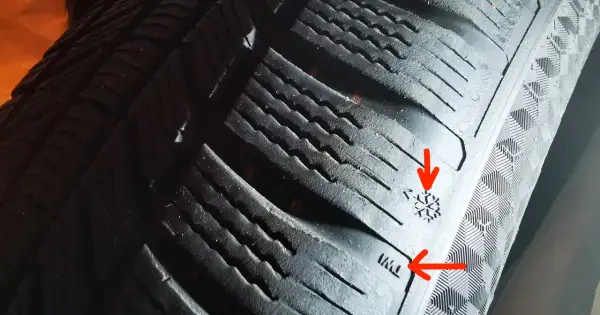 Widoczne są oznaczenia na bieżniku opony, w tym symbol płatka śniegu i wskaźnik zużycia opony.
