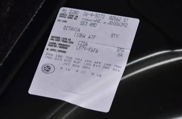 Naklejka z danymi pojazdu, w tym kod silnika po VIN. Widoczny model Octavia, dane techniczne i wyposażenie.