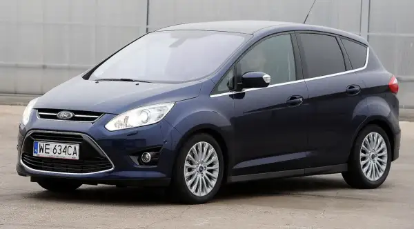 Ciemnoniebieski Ford C-Max, popularny wśród rodzin, widziany z boku. Wiele osób szuka ford c max opinie przed zakupem.