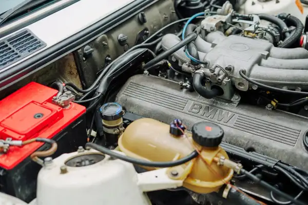 Silnik BMW, czerwony akumulator i zbiornik płynu chłodniczego. Ustalenie części po nr VIN to klucz do sprawnego działania.