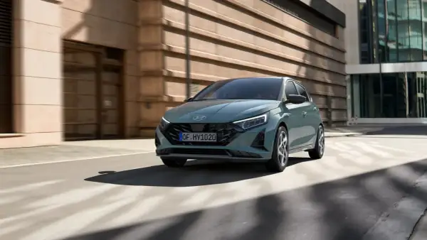 Nowoczesny Hyundai i20 w kolorze zielonym porusza się po miejskiej ulicy. To jeden z wielu stylowych modeli hyundaia.