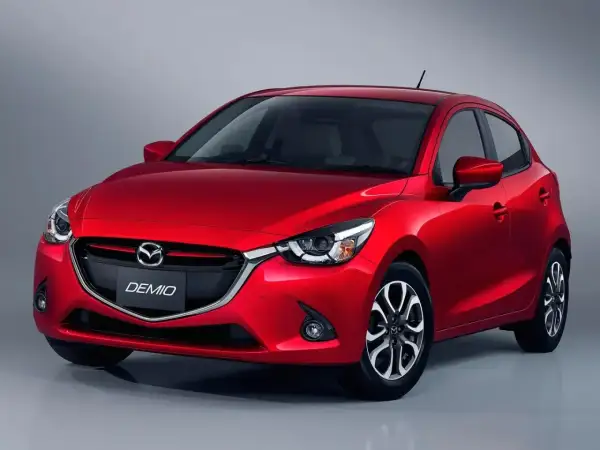 Czerwona Mazda Demio z błyszczącym lakierem i charakterystycznym grillem.