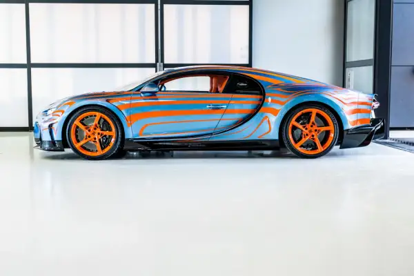 Niebiesko-pomarańczowy Bugatti Chiron Super Sport z dynamicznym wzorem falistych linii i pomarańczowymi felgami.